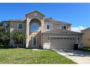 Two story home featuring an arched entryway, attached two-car garage, and front lawn at 402 Big Sioux Ct, Kissimmee, FL 34759