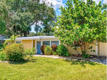 Charming home with a lush green lawn, mature landscaping, and a welcoming blue front door at 706 Lynn Ave, New Smyrna Beach, FL 32168