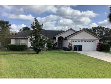 Charming single-story home with a well-manicured lawn, blossoming bushes, and attached two-car garage at 8647 Black Mesa Dr, Orlando, FL 32829