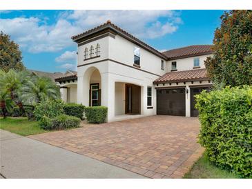 Stunning two-story home with a red tile roof, lush landscaping, and a brick paver driveway and two-car garage at 8752 Lookout Pointe Dr, Windermere, FL 34786