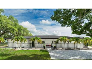 Modern home featuring a fenced front yard, palm trees, and a welcoming paved walkway at 9353 Gotha Rd, Windermere, FL 34786