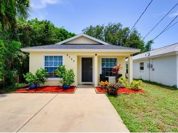 Charming yellow home with inviting front yard and vibrant landscaping under a clear blue sky at 5123 Pineland Ave, Port Orange, FL 32127