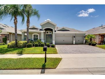Charming single-story home featuring a three-car garage, tropical landscaping, and a paver driveway at 15521 Sandfield Loop, Winter Garden, FL 34787