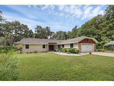 Charming single-story home with a well-manicured lawn, mature trees, and an attached two-car garage at 7838 Sloewood Dr, Mount Dora, FL 32757