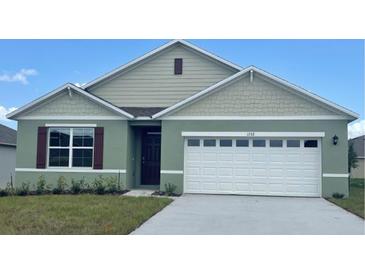 Charming single-Gathering home boasts a well-manicured lawn, two-car garage, and inviting entryway at 910 Princess Sabal Pt, Haines City, FL 33844