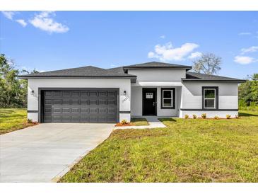 Charming single-story home with a gray garage door, black trim and a well-manicured lawn and inviting curb appeal at 15684 Sw 37Th Cir, Ocala, FL 34473