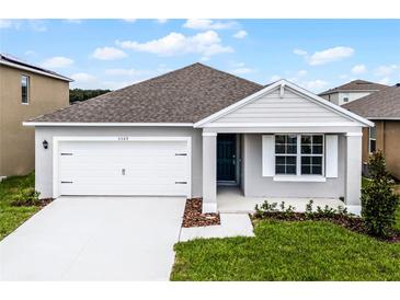Charming single-story home featuring a two-car garage, a welcoming front porch, and a well-maintained lawn at 5162 Marshelder St, Apopka, FL 32712