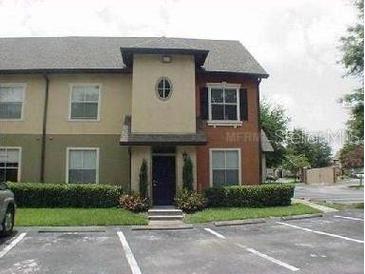 Two-story condo with manicured bushes, neutral paint, and dedicated parking spaces in front of the unit at 5953 Westgate Dr # 1821, Orlando, FL 32835