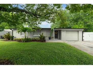 Charming single-story home featuring a manicured lawn, mature trees, and a welcoming front entrance at 654 Romano Ave, Orlando, FL 32807