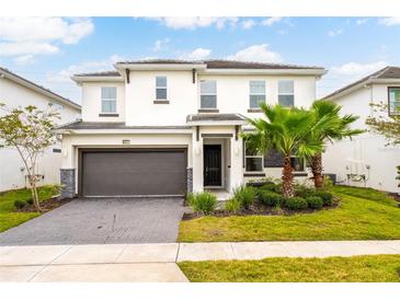 Charming two-story home featuring a two-car garage, lush landscaping, and a well-manicured lawn at 2613 Calistoga Ave, Kissimmee, FL 34741