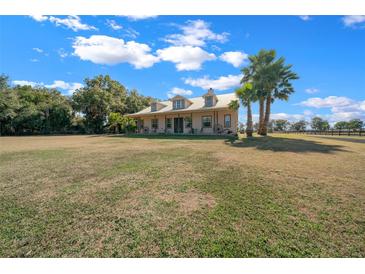 Charming home with a metal roof, dormers, and a wide front porch, surrounded by a green lawn and mature trees at 2198 W Highway 329, Citra, FL 32113