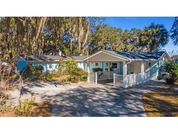 Light blue house with white accents, carport, and mature trees at 22345 Ne 108Th Avenue Rd, Fort Mc Coy, FL 32134