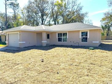 Tan one-story house with a garage and a yard at 6044 Nw 65Th Pl, Ocala, FL 34482