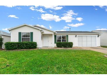 Cute one-story house with green shrubs and a two-car garage at 7994 Se 174Th Belhaven Loop, The Villages, FL 32162