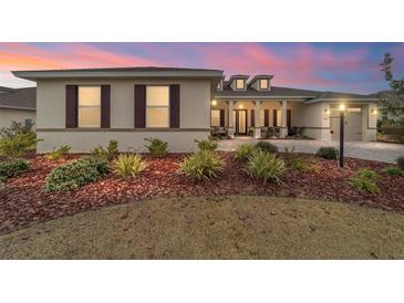 Beautiful single-story home with manicured landscaping, decorative shutters and covered front porch with sunset skies at 8160 Sw 92Nd Cir, Ocala, FL 34481