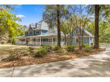 Two-story house with a wrap-around porch and mature landscaping at 7629 Sw 188 Ave, Dunnellon, FL 34432