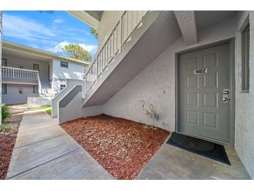 Gray building exterior with walkway, stairs, and landscaping at 567 Midway Trak # H102, Ocala, FL 34472