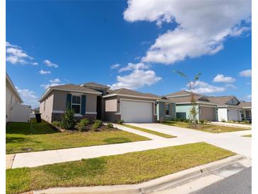 Charming one-story home with a well-manicured lawn and attached two-car garage under a sunny blue sky at 6396 Sw 72Nd Ter, Ocala, FL 34474