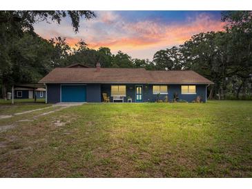 Charming single-story home with a vibrant blue exterior and well-maintained lawn at 15235 Se 63Rd Ave, Summerfield, FL 34491