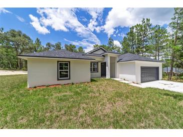 Single-story home with gray garage door and landscaping at 4444 Sw 118 Ter, Ocala, FL 34481