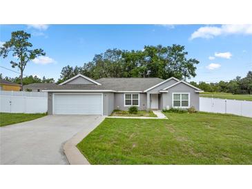 Charming single-story home with gray exterior, attached garage, and well-maintained green lawn at 253 Locust Pass Loop, Ocala, FL 34472