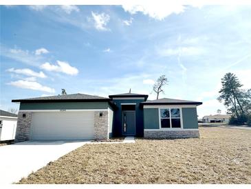 Inviting single-story home boasts stone accents, a two-car garage, and a well-maintained lawn at 4544 Sw 156 Pl, Ocala, FL 34473