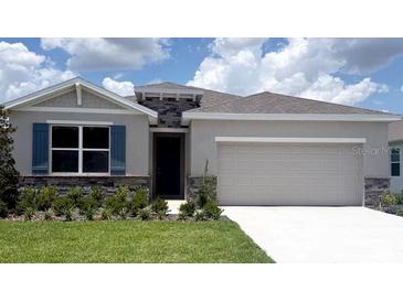 Charming single-story home with stone accents, blue shutters, a two car garage, and a well-manicured lawn at 3148 Canopy Oak Blvd, Wildwood, FL 34785