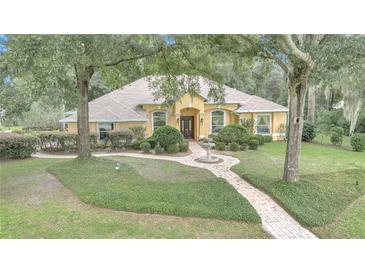 Charming yellow home featuring a brick path and fountain leading to the front door at 19057 Sw 98Th Loop, Dunnellon, FL 34432