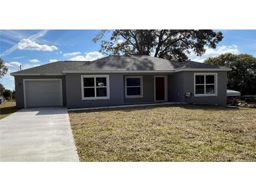 Newly constructed home with gray exterior, driveway, and grassy lawn at 4030 Se 134Th St, Belleview, FL 34420