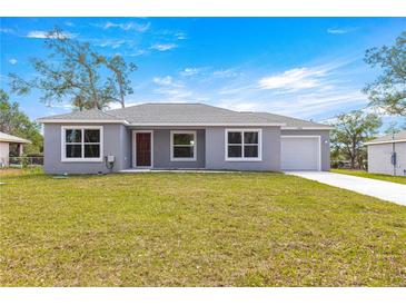 Charming single-story home with a well-manicured lawn, gray exterior, and a one-car garage at 4030 Se 134Th St, Belleview, FL 34420