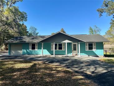 Charming home featuring blue siding, white trim, and a well-maintained front yard at 5877 Nw 64Th St, Ocala, FL 34482