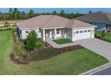 Charming single-story home featuring a well-manicured lawn, brick driveway and a two-car garage at 9400 Sw 106Th Ave, Ocala, FL 34481