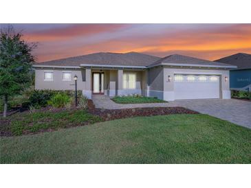 Charming single-story home boasts a manicured lawn, a paver walkway, and a pristine three-car garage at 9400 Sw 106Th Ave, Ocala, FL 34481
