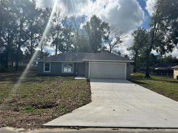 Charming one-story home with a fresh concrete driveway and attached two car garage at 3 Dogwood Trl, Ocala, FL 34472