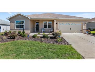 Inviting single-story home with a manicured lawn, tasteful landscaping, and charming front porch seating at 8823 Sw 104Th Cir, Ocala, FL 34481