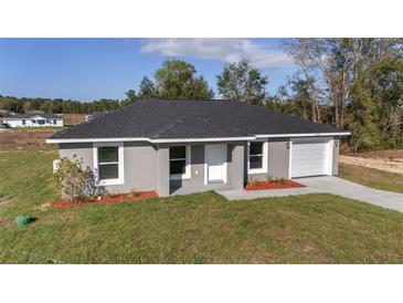 Charming single-story home featuring a gray exterior, attached garage, and well-manicured front yard at 15390 Sw 10 Pl, Ocala, FL 34481