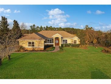Single-story home with stucco exterior, landscaped lawn, and a two-car garage at 6925 Se 96Th Place Rd, Belleview, FL 34420