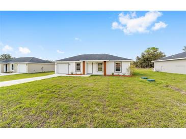 Charming single-story home with a well-manicured front lawn and a driveway leading to the garage at 14363 Sw 27 St, Ocala, FL 34481