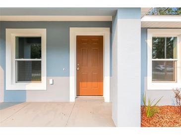 Inviting front entry with a solid wood door, white trim, and modern exterior color palette at 15282 Sw 27 Ln, Ocala, FL 34481