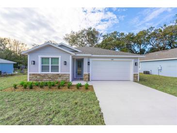 Newly constructed home with gray siding, stone accents, and a two-car garage at 13850 Se 42Nd Ave, Summerfield, FL 34491