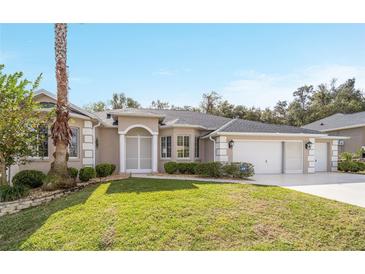 Tan house with a three-car garage and manicured lawn at 5874 Nw 18Th Pl, Ocala, FL 34482