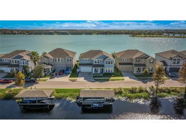 Aerial view of waterfront homes showcasing boat docks, lake views, and well manicured lawns on a sunny day at 455 Blue Cypress Dr, Groveland, FL 34736