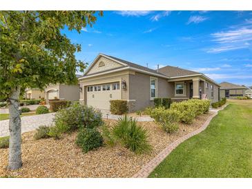 Tan one-story house with landscaping and a two-car garage at 9870 Sw 99Th Loop, Ocala, FL 34481