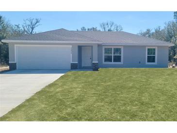 Charming single-story home featuring a well-manicured lawn, a two car garage, and a welcoming entrance at 22084 Sw Rainbow Lakes Blvd, Dunnellon, FL 34431