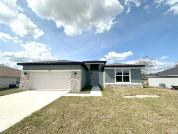 Charming single-story home featuring stone accents, a two-car garage, and a well-manicured lawn at 3015 Sw 132Nd St, Ocala, FL 34473