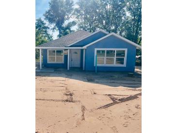 Charming blue home featuring crisp white trim and a new roof nestled among mature trees at 14319 Se 26Th Ter, Summerfield, FL 34491