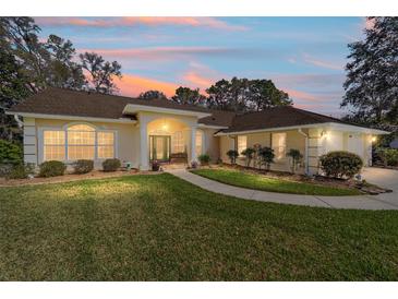 Inviting single Gathering home with manicured lawn and beautiful exterior lighting at sunset at 19009 Sw 98Th Loop, Dunnellon, FL 34432