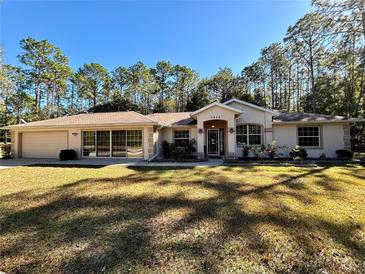 Charming one-story home featuring lush landscaping, a welcoming entrance, and an attached two-car garage at 7535 Sw 185 Avenue Rd, Dunnellon, FL 34432
