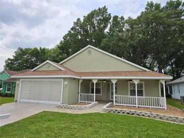 Inviting single-story home with a charming front porch, manicured lawn, and a convenient two-car garage at 10975 Sw 69Th Cir, Ocala, FL 34476