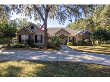 Single-story home with stone accents, landscaping, and a large driveway at 5425 Se 44Th Cir, Ocala, FL 34480